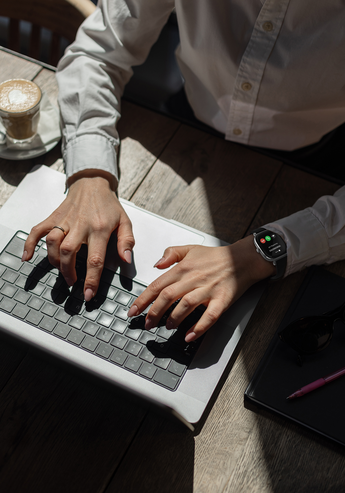Person typing on a laptop with a cup of coffee and notebook in the background