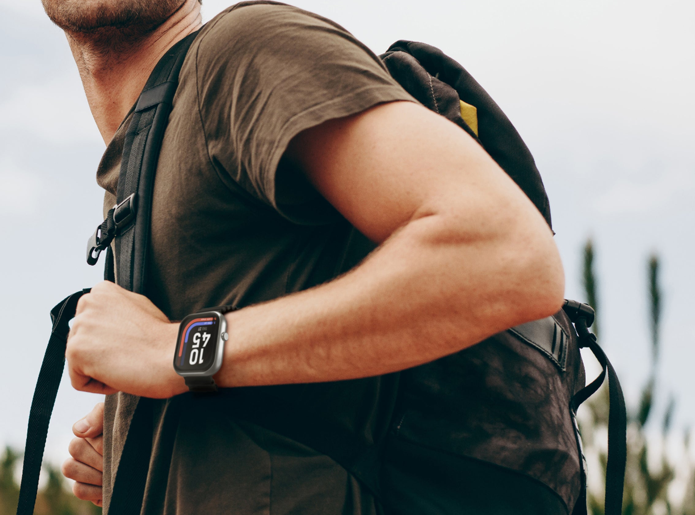Person wearing a smartwatch with a backpack outdoors
